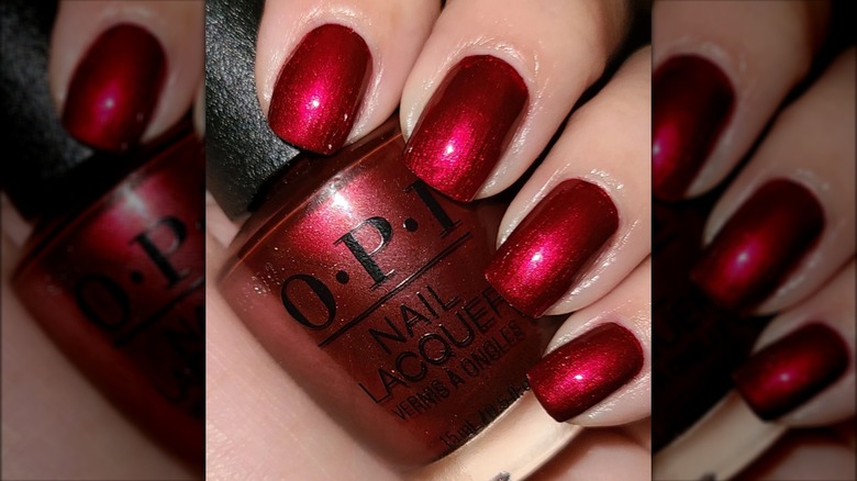 Hand holding red OPI nail polish
