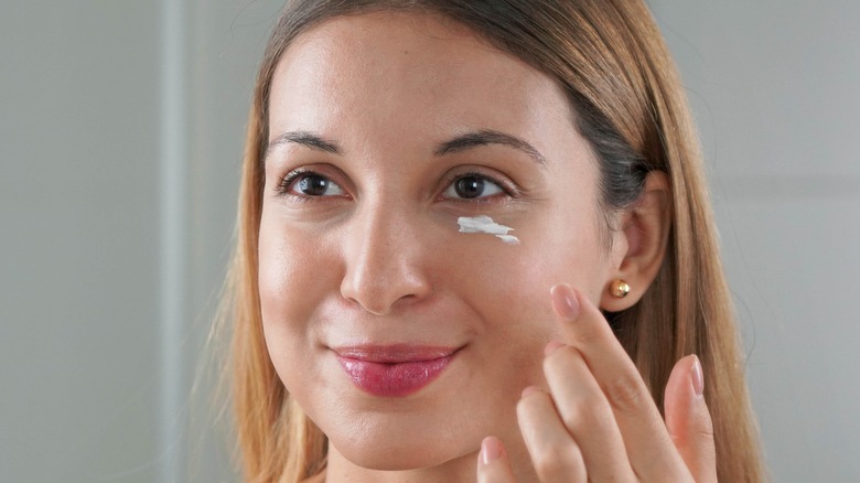 Model applying eye cream