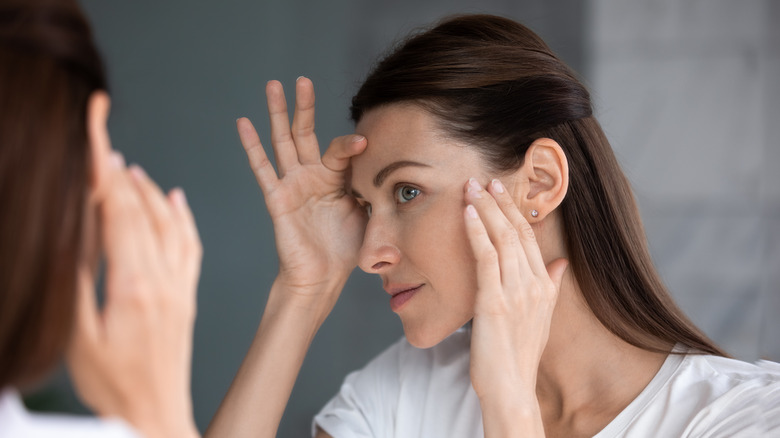 woman looking at her wrinkles in the mirror 