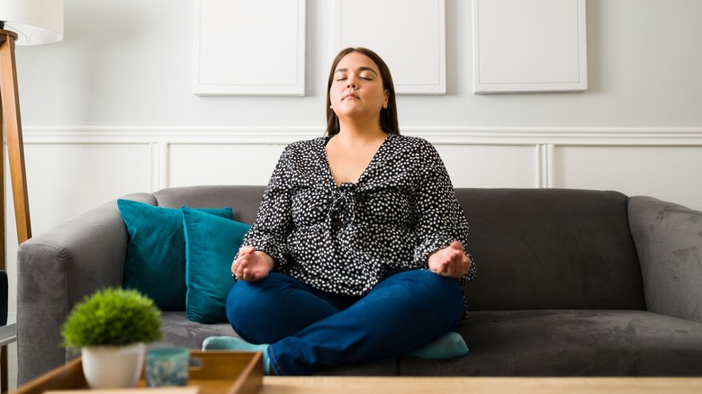 women closes eyes on couch to meditate