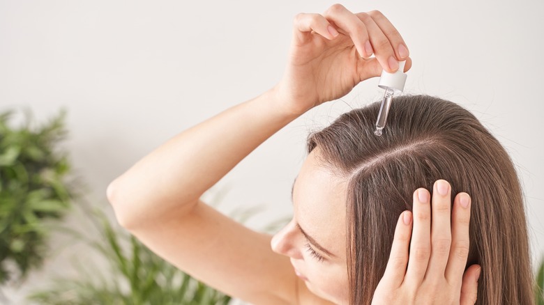 woman applying oil to scalp