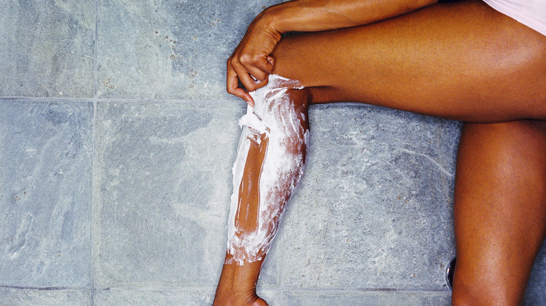woman shaving leg in tub