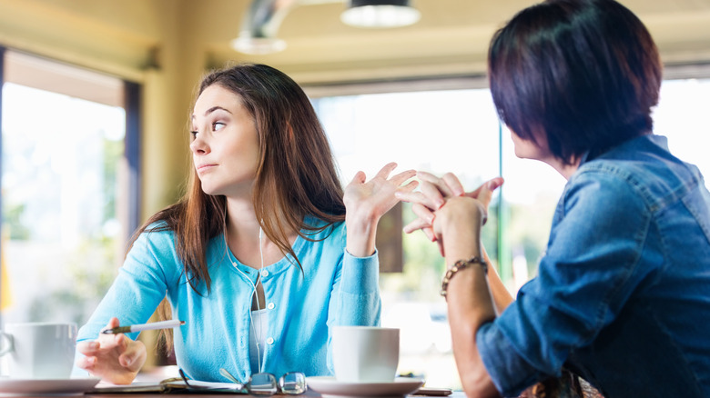 Friend gestures dismissively over coffee 