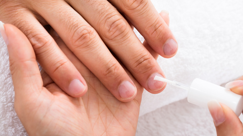 person applying clear nail polish