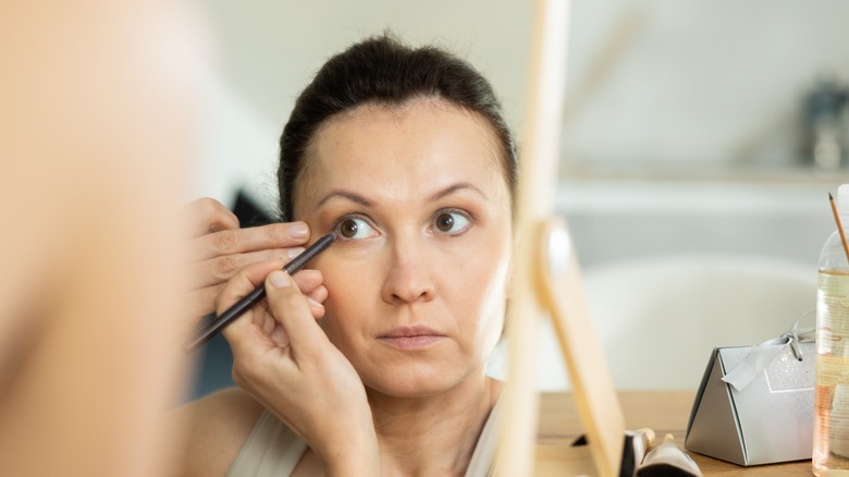 A woman using a brush to line her eyes