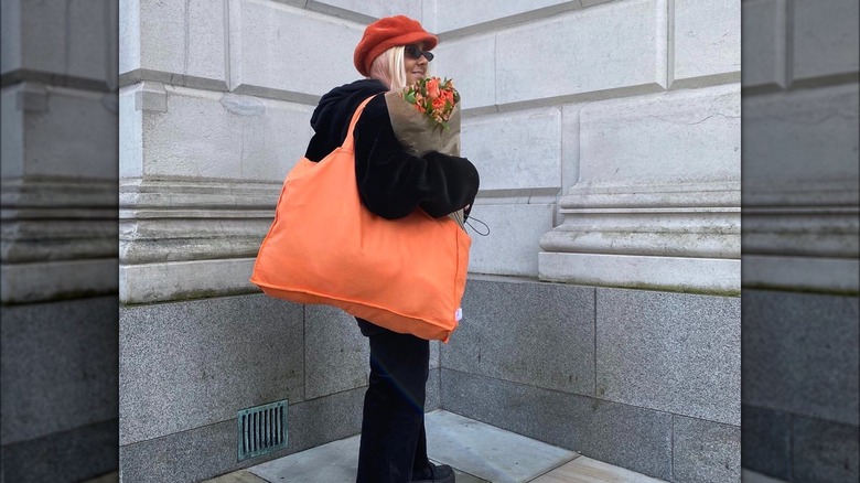 Woman posing with orange tote