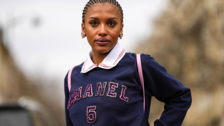 Woman with cornrows and collared Chanel sweatshirt