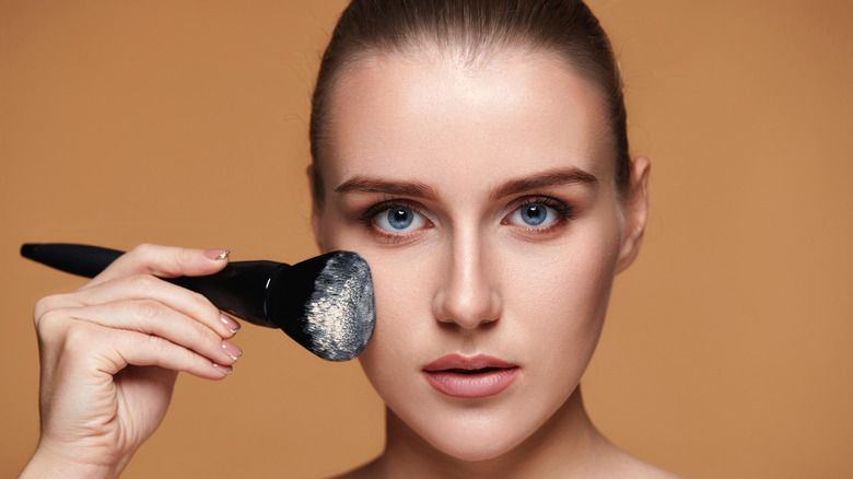 Woman applying setting powder to face