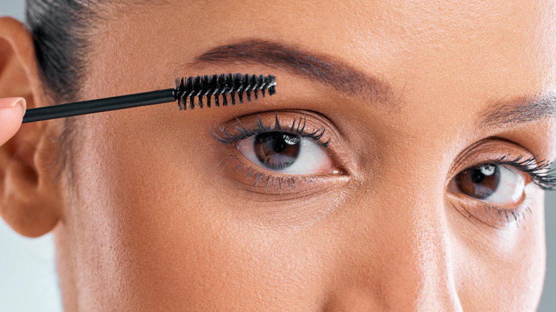 woman applying mascara with a spoolie