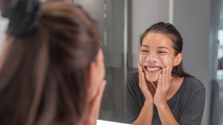 Woman washing face in mirror