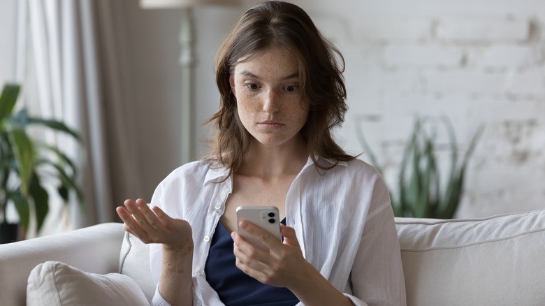 Woman questioningly looks at phone