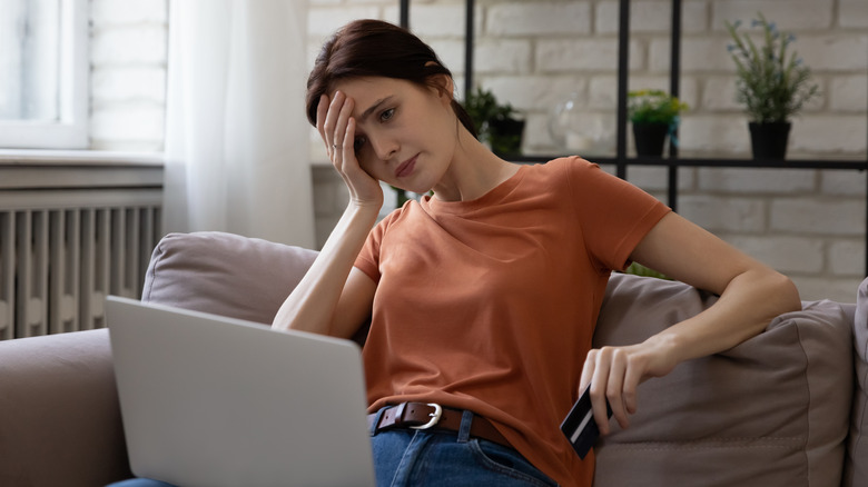 Stressed out woman checks bank account on laptop