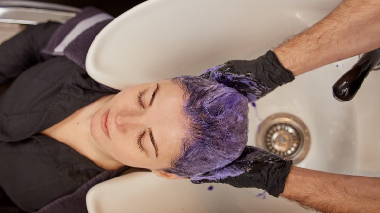 person washing hair with purple shampoo