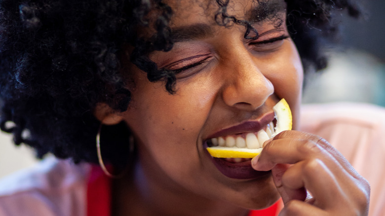 Woman biting into lemon slice