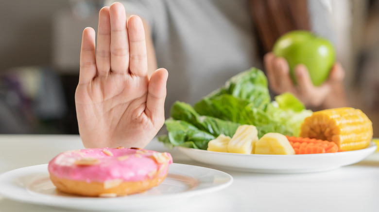 woman rejecting a donut for vegetables