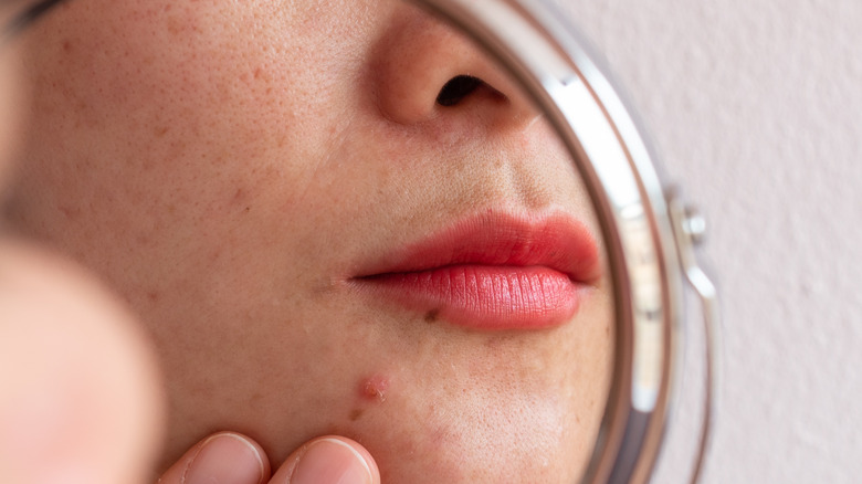 woman looking at her lips in mirror