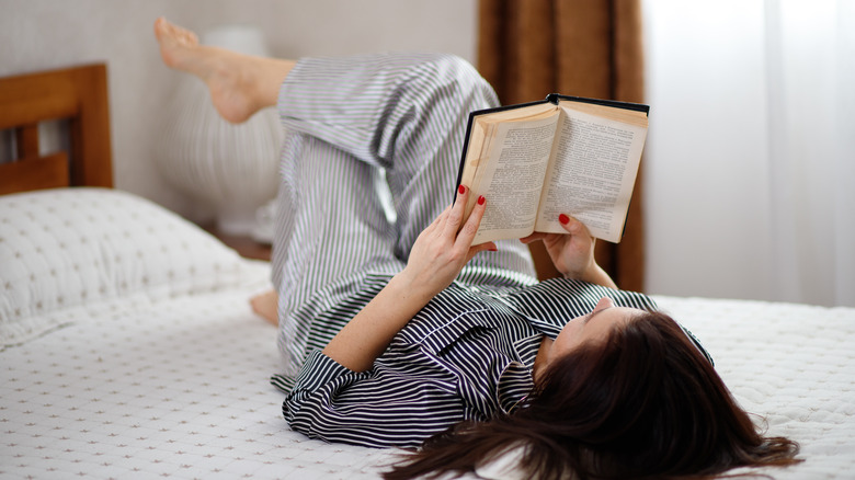 person in bed with book