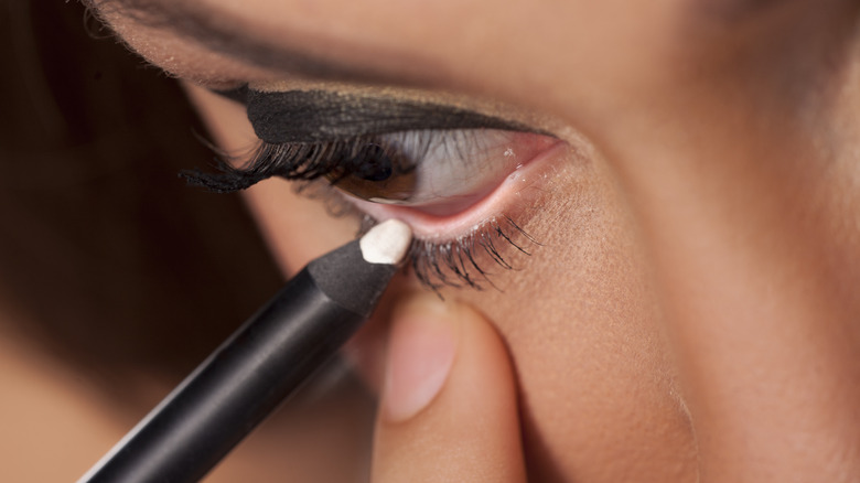 woman applying white eyeliner