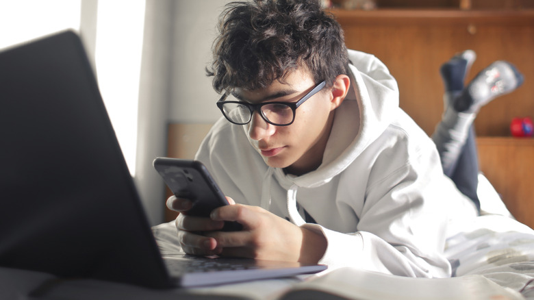 Boy studying on his phone in bed