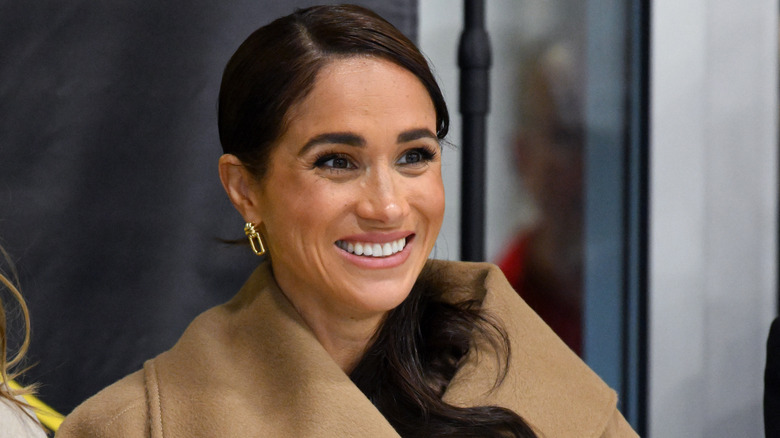 Meghan Markle wearing a beige coat and gold earrings