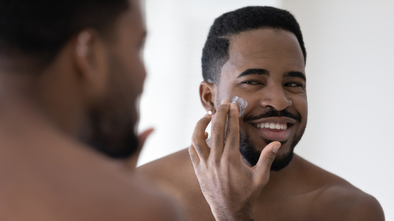 Man applying sunscreen in mirror