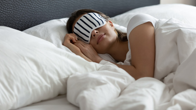 Person sleeping in bed with sleep mask