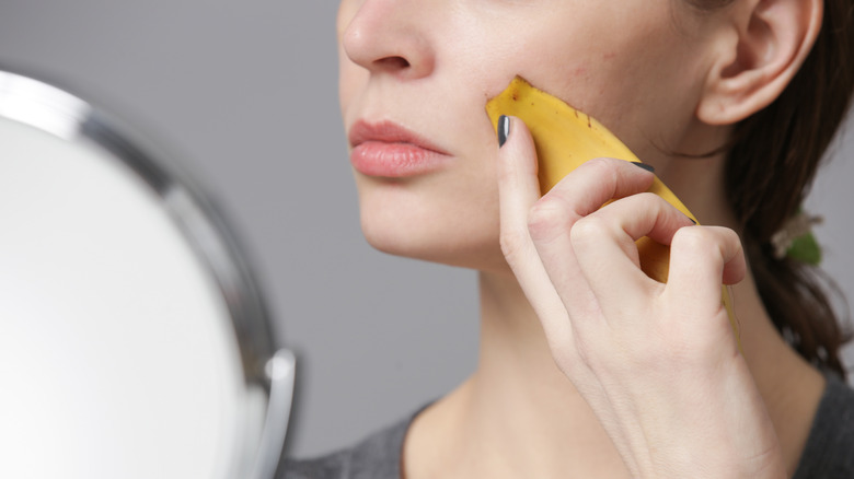 Woman putting banana skin on face