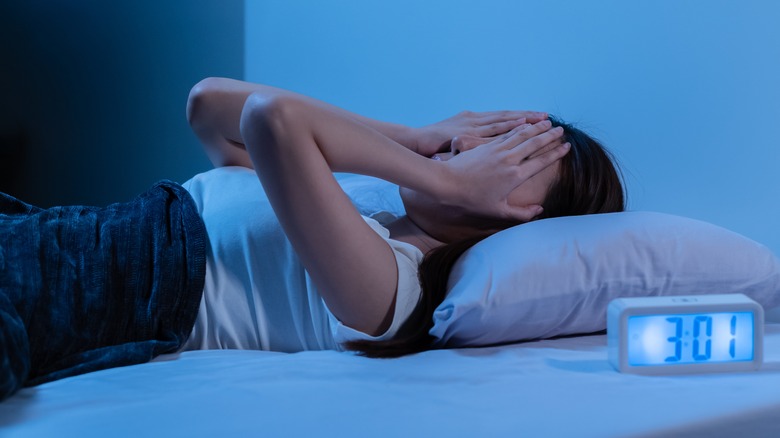 Person on bed covering face