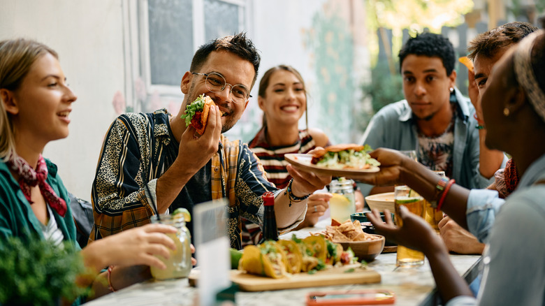 A group of friends sharing tacos and laughing together.