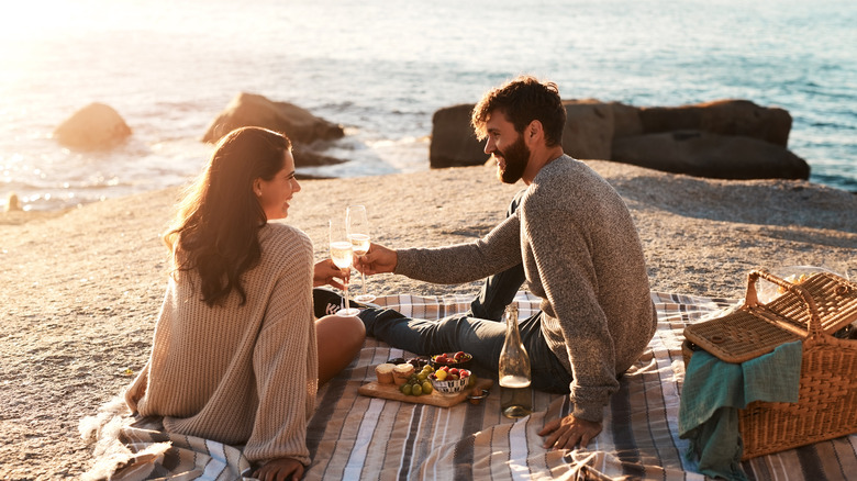 A happy couple having a romantic picnic on the beach.