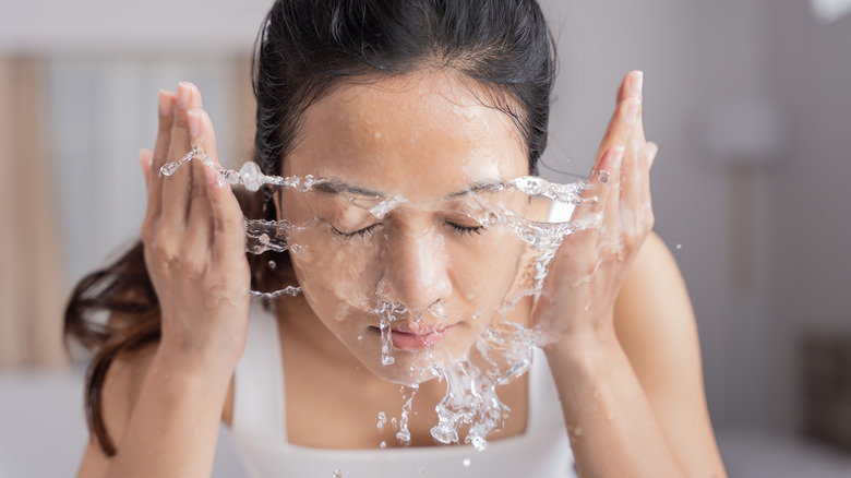 Woman rinsing her face with water after cleansing