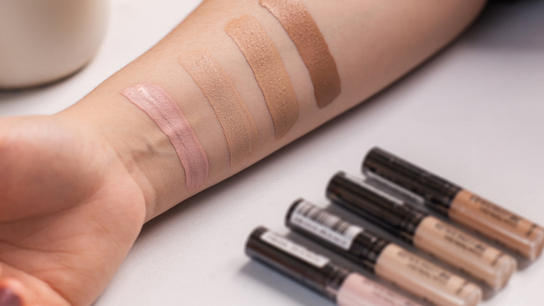 Person swatching four shades of concealer on inner arm