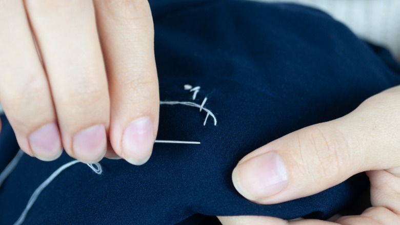 Close up of hand sewing a stitch