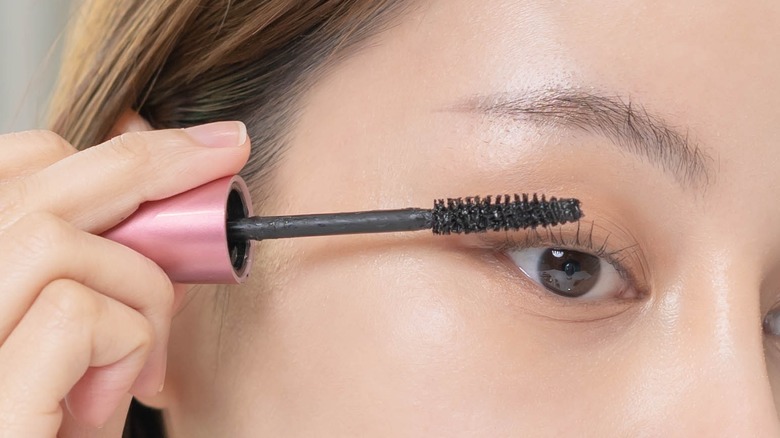 woman applying mascara on lashes