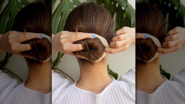 woman styling hair into bun 