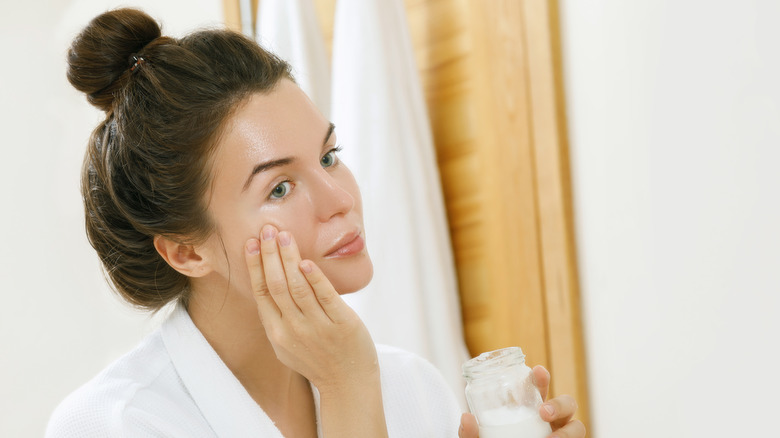 Woman applying cream to face