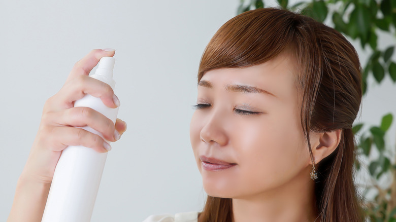 Asian woman spraying mist on face