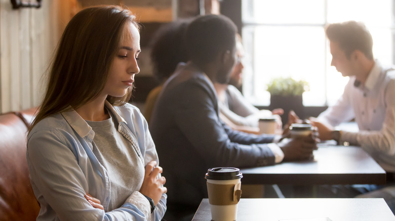 Angry woman with arms crossed sitting in a coffee shop