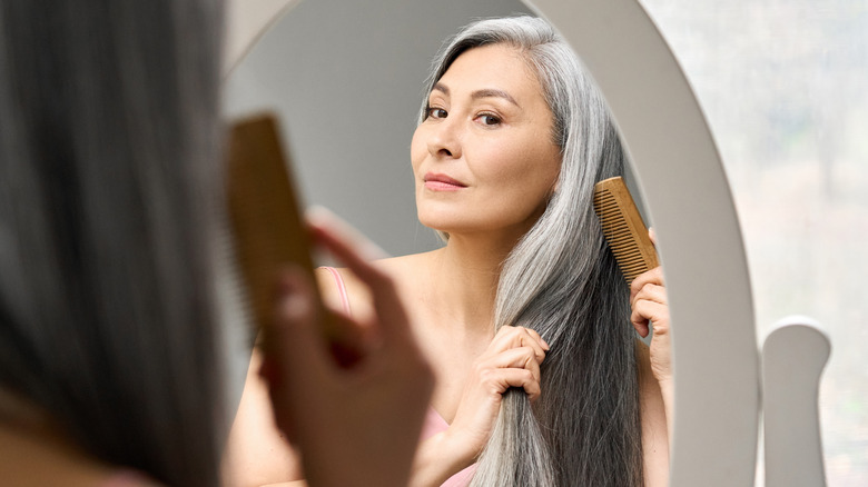 Mature woman combs and examines hair