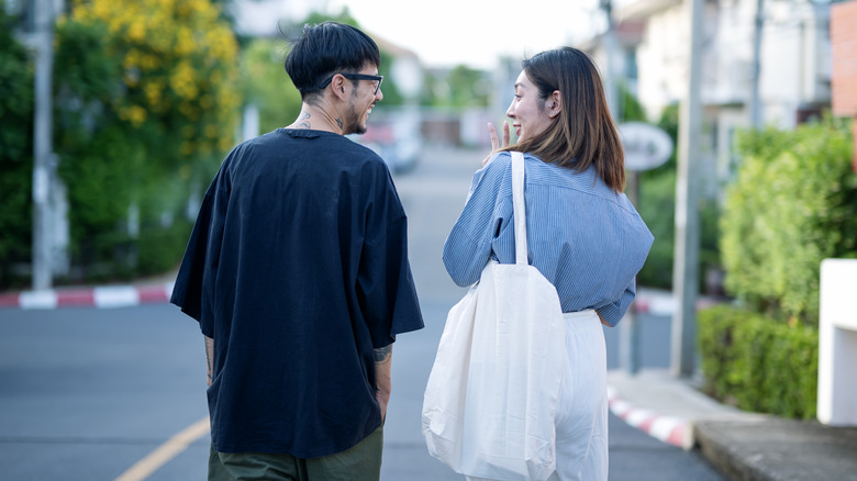 Two people walking and talking down a suburban street.