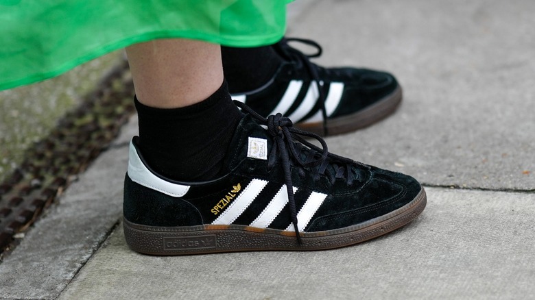 women wearing black Adidas sneakers