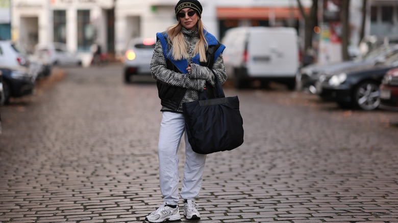 woman wearing vest, sweater, pants, and chunky running shoes