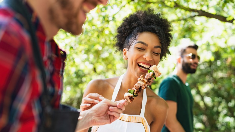 Guy handing kabob to woman