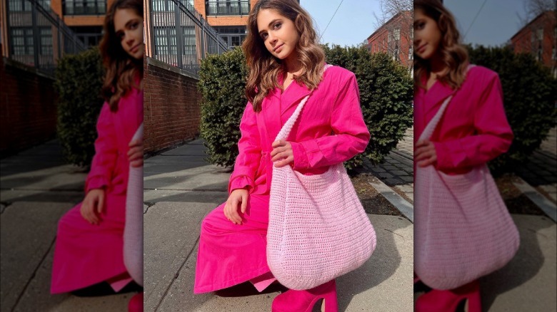 Woman models pink crocheted purse 