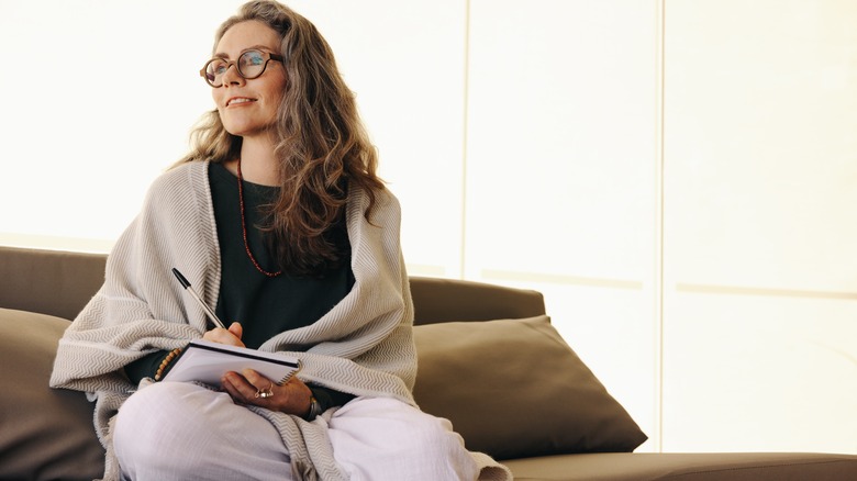 Woman happily contemplates while writing in journal 