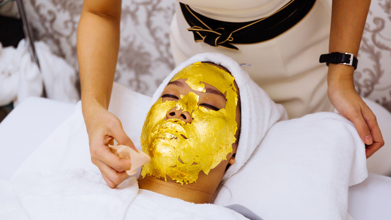 Woman receiving gold facial mask