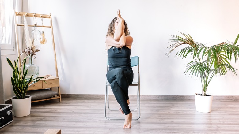 Woman doing eagle pose in chair