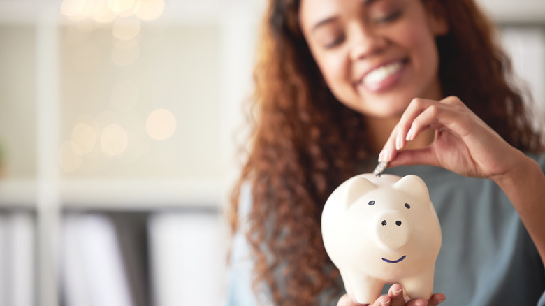 Woman adding to piggy bank 