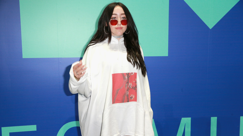 Noah Cyrus with black hair and red sunglasses