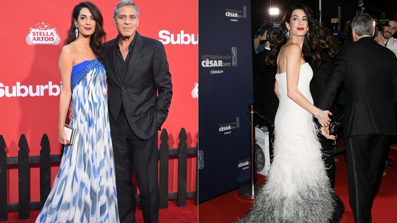 Amal Clooney in a white dress with feather detail, and standing next to George Clooney in a blue and white dress